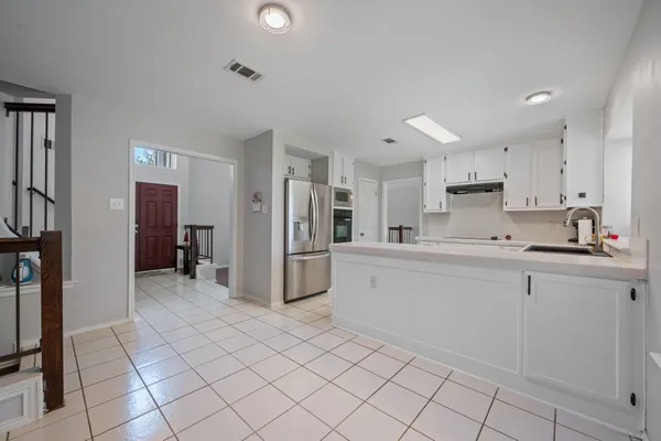 a large white kitchen with cabinets and stainless steel appliances