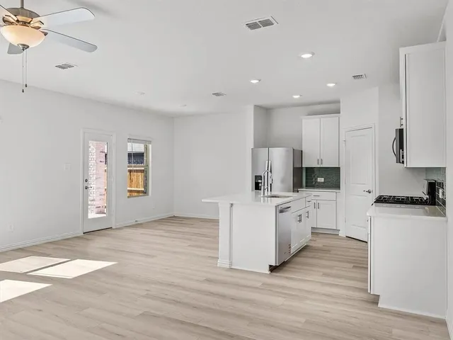 a kitchen with kitchen island a sink a stove a microwave and wooden floor