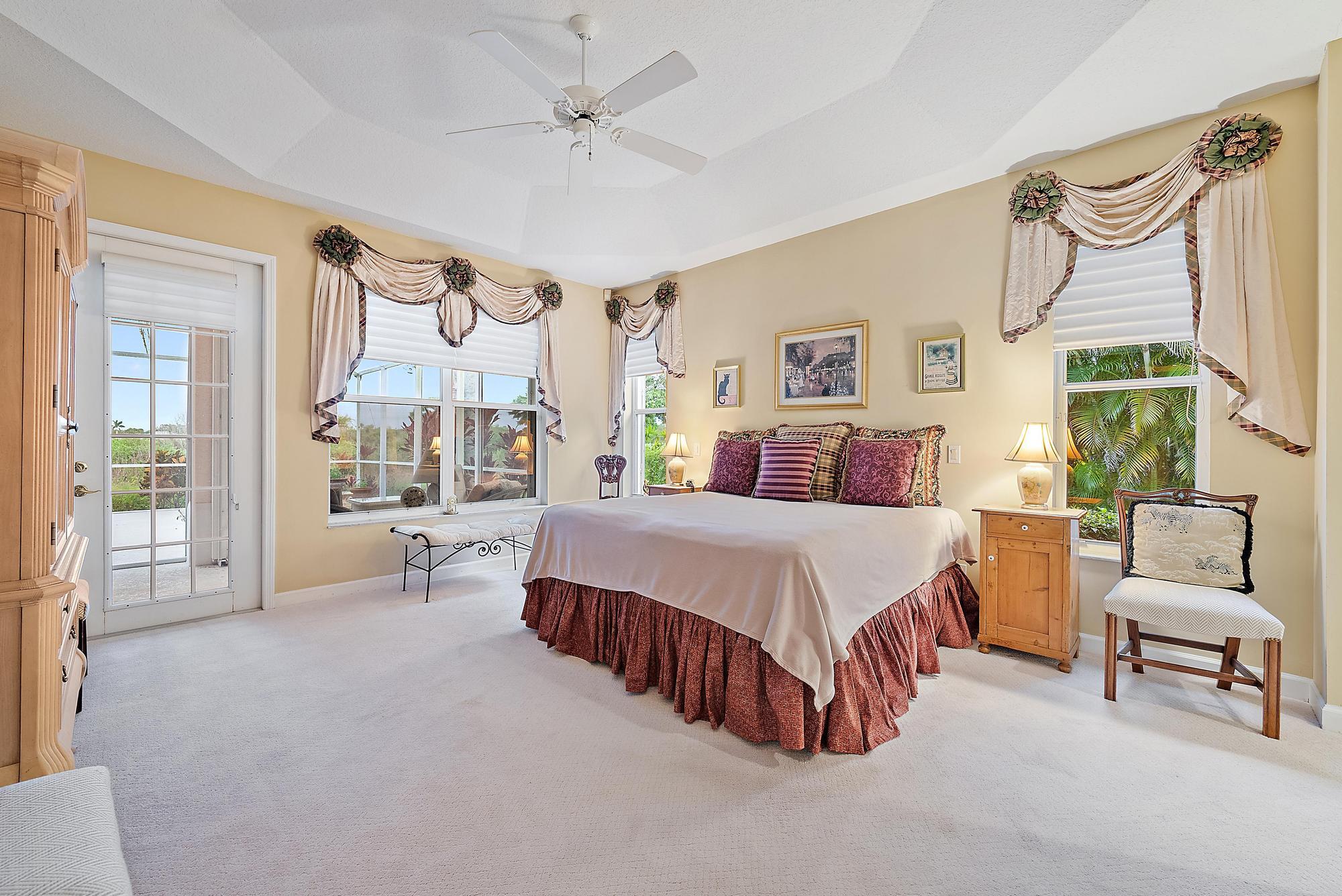 8157 Southeast Double Tree Drive Hobe Sound, FL 33455 - Photo 16 of 46 a spacious bedroom with a bed a couch and a large window