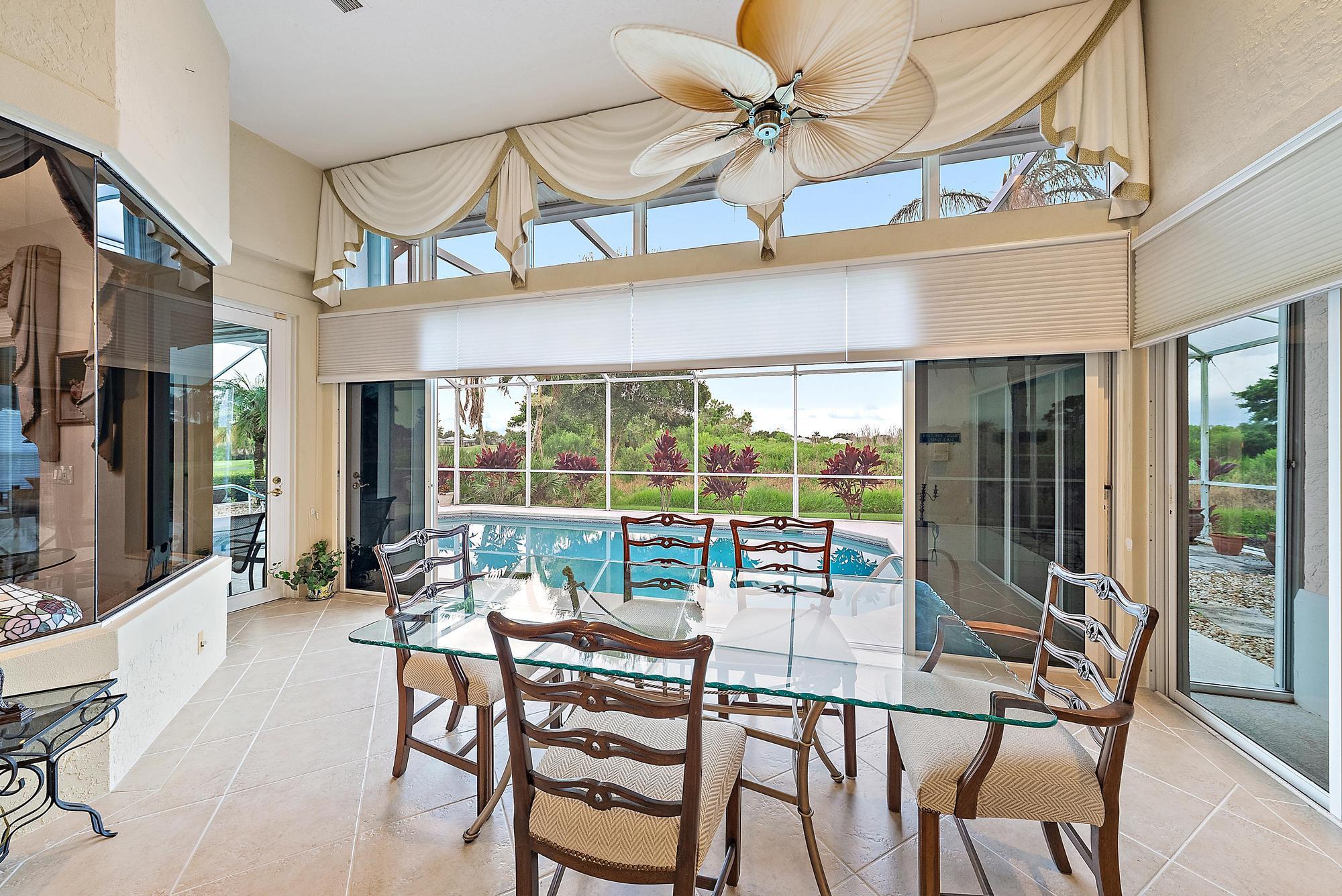 8157 Southeast Double Tree Drive Hobe Sound, FL 33455 - Photo 8 of 46 a view of a dining room with furniture large windows and a chandelier