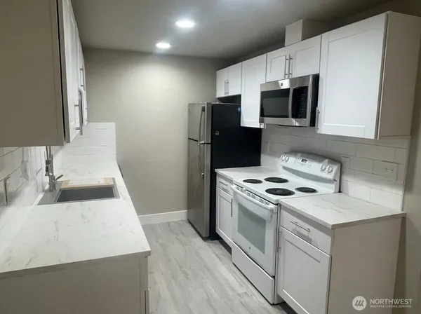 a kitchen with stainless steel appliances a sink a stove a microwave a refrigerator a counter space and cabinets