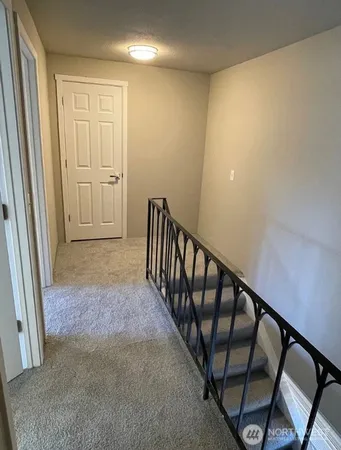 a view of a hallway with wooden floor and stairs