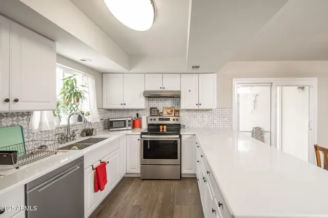 a kitchen with granite countertop a sink stainless steel appliances and white cabinets