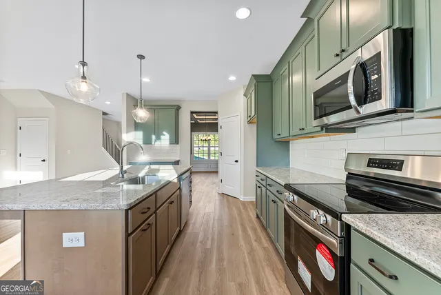 a kitchen with stainless steel appliances granite countertop a sink a stove and a wooden floors