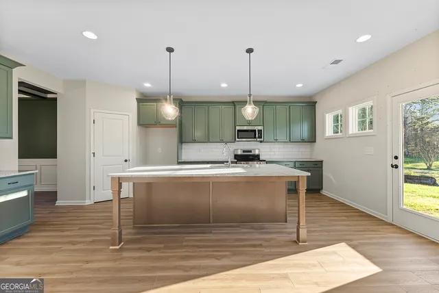 a view of a kitchen with kitchen island a sink wooden floor and a chandelier