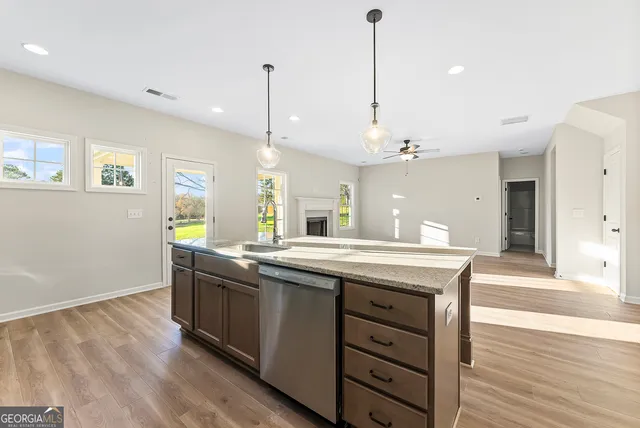 a kitchen with stainless steel appliances granite countertop a sink a stove and a wooden floor