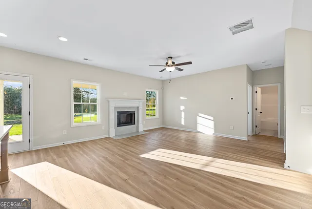a view of an empty room with window and wooden floor