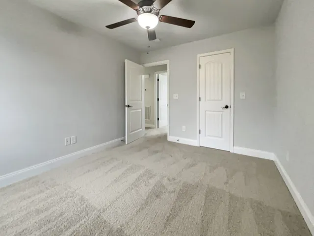 a view of an empty room and chandelier fan