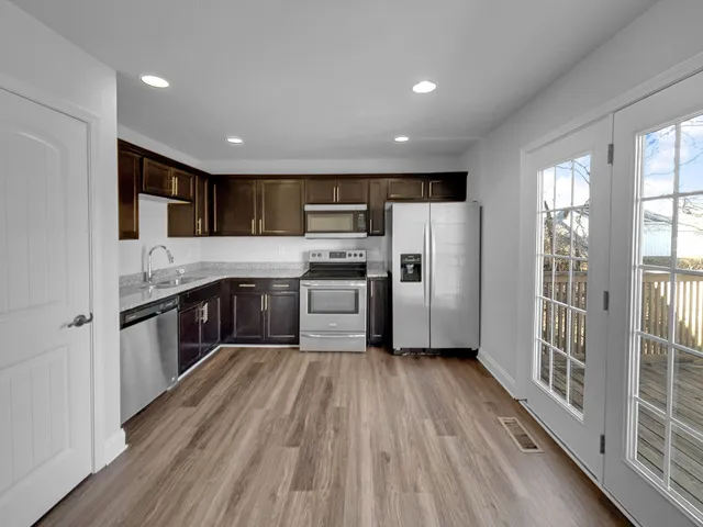 a kitchen with stainless steel appliances granite countertop a refrigerator a sink dishwasher a stove and a oven with wooden floor