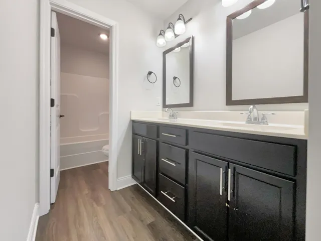 a en suite bathroom with a double vanity sink a mirror and a bathtub