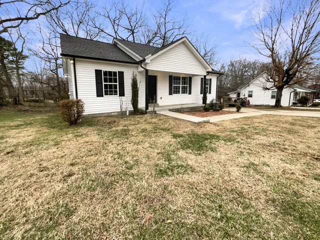 a view of a yard in front of a house with large tree