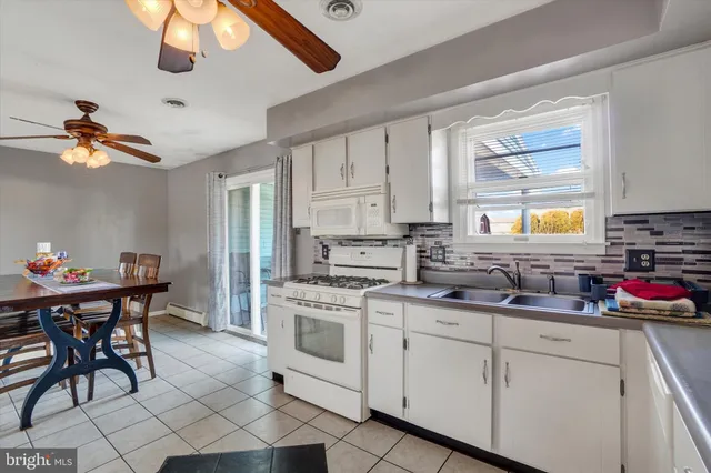 a kitchen with stainless steel appliances granite countertop a stove a sink dishwasher and white cabinets with wooden floor