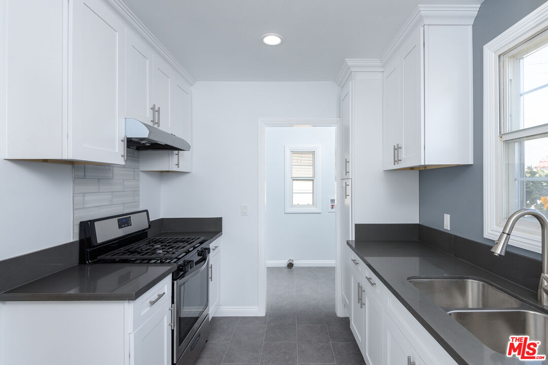 2107 West 84th Place Los Angeles, CA 90047 - Photo 13 of 25 a kitchen with granite countertop a sink stove and cabinets