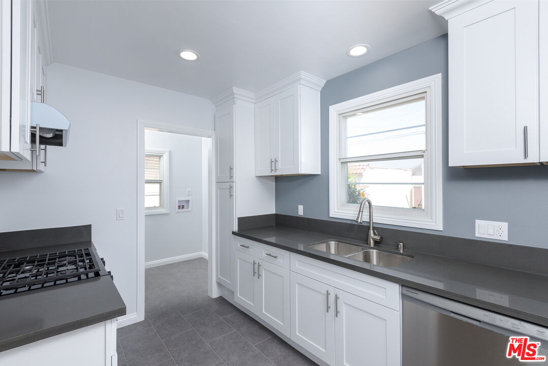 2107 West 84th Place Los Angeles, CA 90047 - Photo 14 of 25 a kitchen with granite countertop a sink stove and cabinets