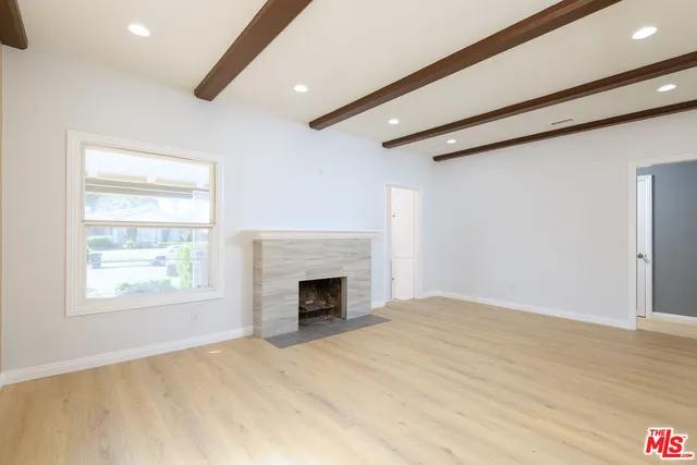 a view of empty room with fireplace and wooden floor
