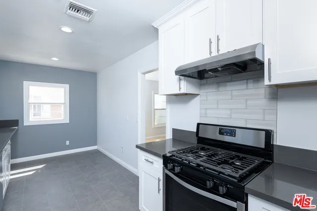 a kitchen with stainless steel appliances granite countertop a stove and a wooden cabinets