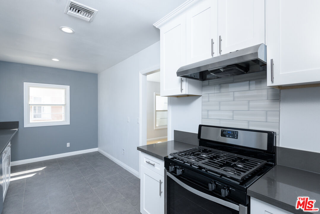 2107 West 84th Place Los Angeles, CA 90047 - Photo 9 of 25 a kitchen with stainless steel appliances granite countertop a stove and a wooden cabinets
