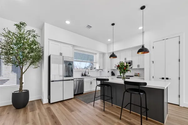 a kitchen with kitchen island white cabinets and stainless steel appliances