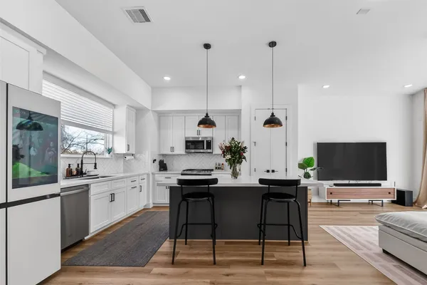 a room with stainless steel appliances kitchen island granite countertop a sink and cabinets