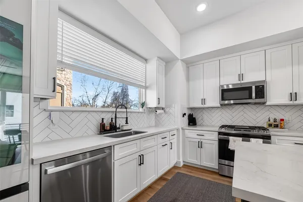 a kitchen with stainless steel appliances white cabinets and a window