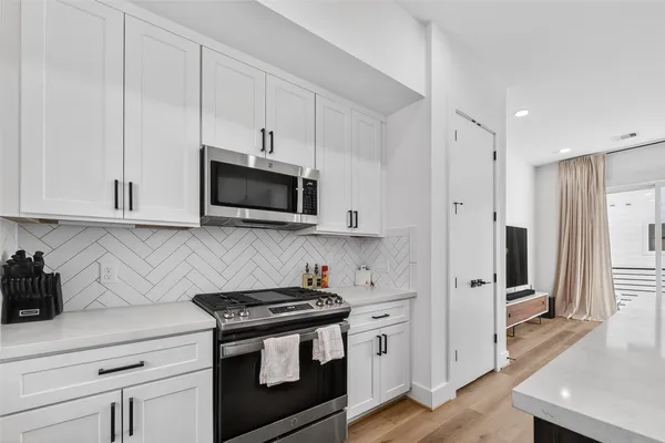 a kitchen with stainless steel appliances granite countertop a stove a microwave and a refrigerator