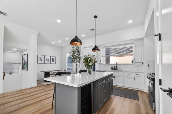 a large kitchen with stainless steel appliances a sink and a wooden floor