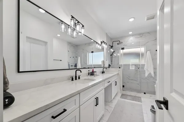 a bathroom with a double vanity sink a mirror and shower