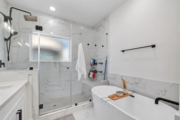 a bathroom with a tub sink mirror and shower