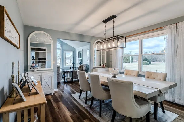 a dining room with wooden floor a chandelier a wooden table and chairs