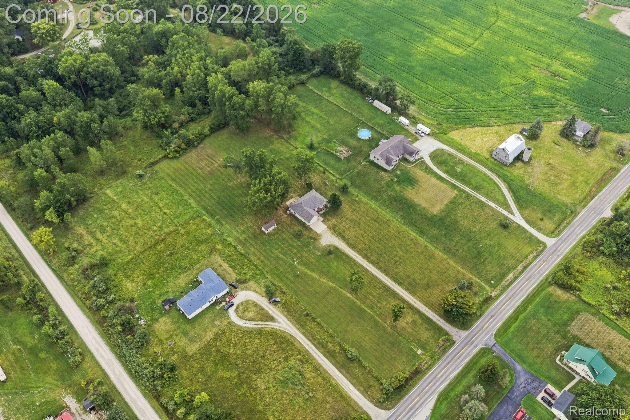 1301 Palms Road Columbus, MI 48063 - Photo 5 of 51 Expansive property featuring multiple structures, verdant fields, a wooded perimeter, and established roadways