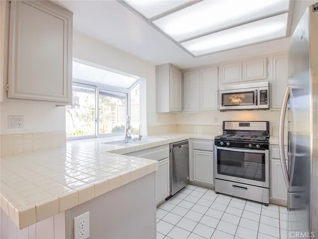 a kitchen with granite countertop a refrigerator stove microwave and sink