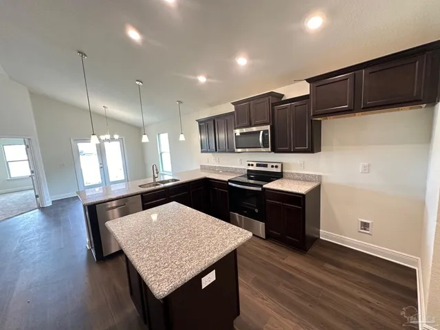 a kitchen with a stove a sink a microwave a refrigerator and cabinets