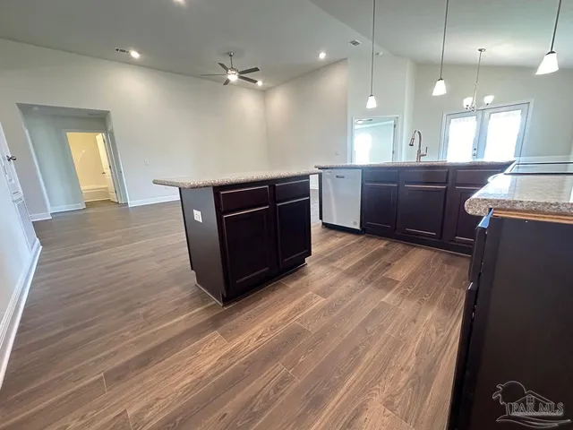 a room with stainless steel appliances kitchen island wooden floors and view living room