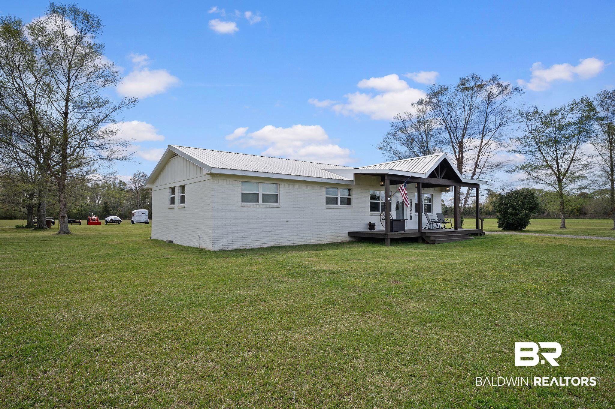 24924 Brewer Road Robertsdale, AL 36567 - Photo 3 of 33 Side of property with a lawn and metal roof
