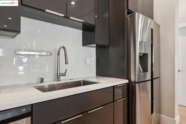 a kitchen with stainless steel appliances kitchen island granite countertop a stove a sink a refrigerator and a dining table with wooden floor