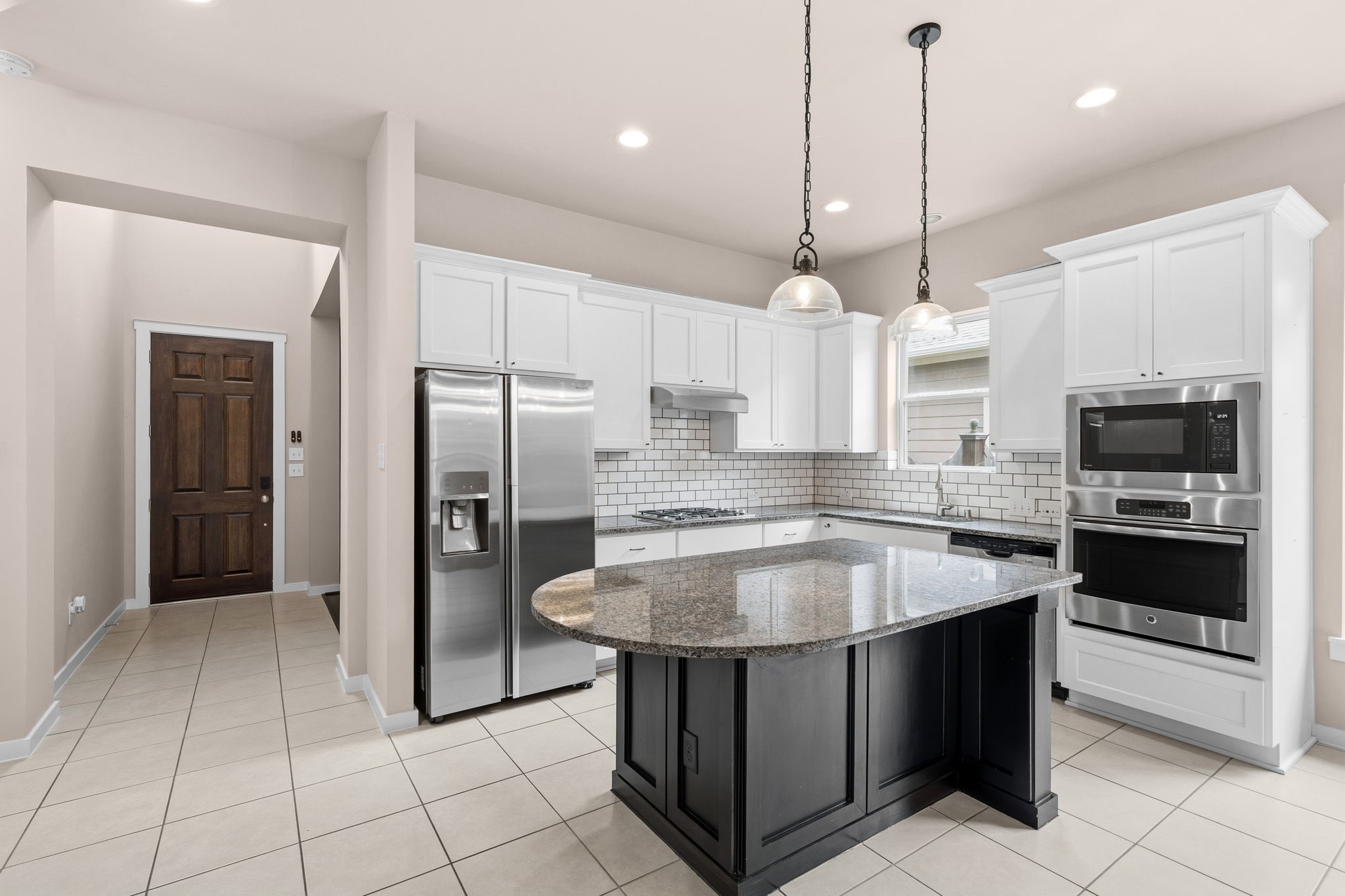 17019 Seminole Ridge Drive Cypress, TX 77433 - Photo 11 of 48 Updated kitchen featuring white cabinetry, granite countertops, and a contrasting island for added prep space. Stainless steel appliances, subway tile backsplash, and stylish pendant lighting complete this bright, functional layout.