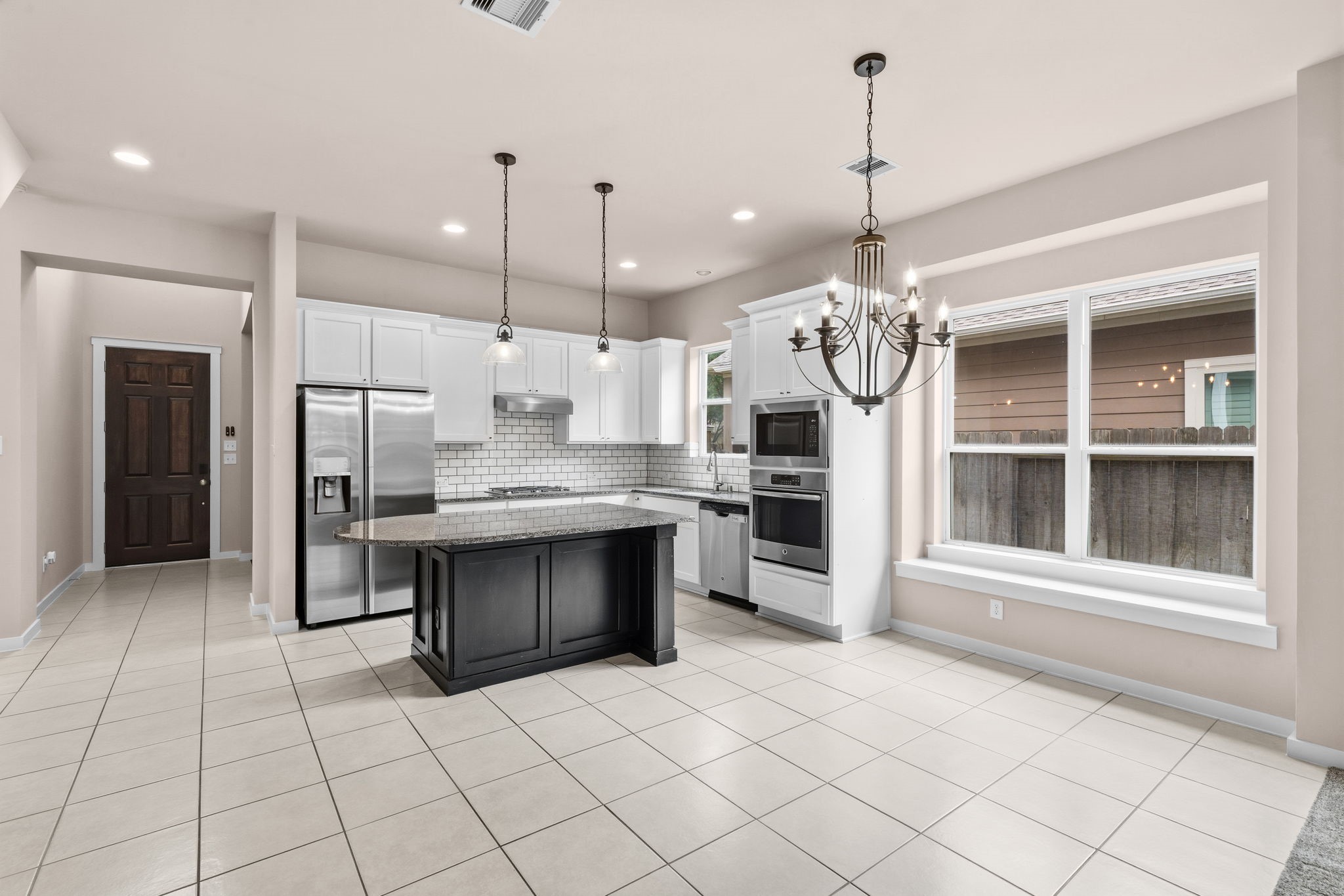 17019 Seminole Ridge Drive Cypress, TX 77433 - Photo 13 of 48 Open-concept kitchen and dining area with granite island, white cabinetry, and stainless steel appliances. Elegant chandelier and pendant lighting add style, while large windows bring in abundant natural light.