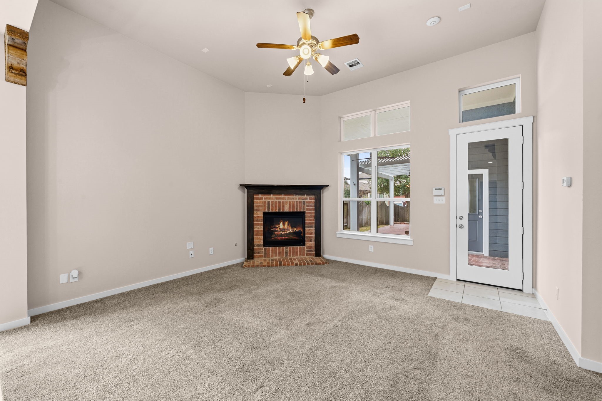 17019 Seminole Ridge Drive Cypress, TX 77433 - Photo 15 of 48 Bright and inviting living area featuring soaring ceilings, a cozy brick fireplace, and abundant natural light. Neutral tones, plush carpeting, and an open layout create a warm and welcoming space perfect for everyday living and entertaining.