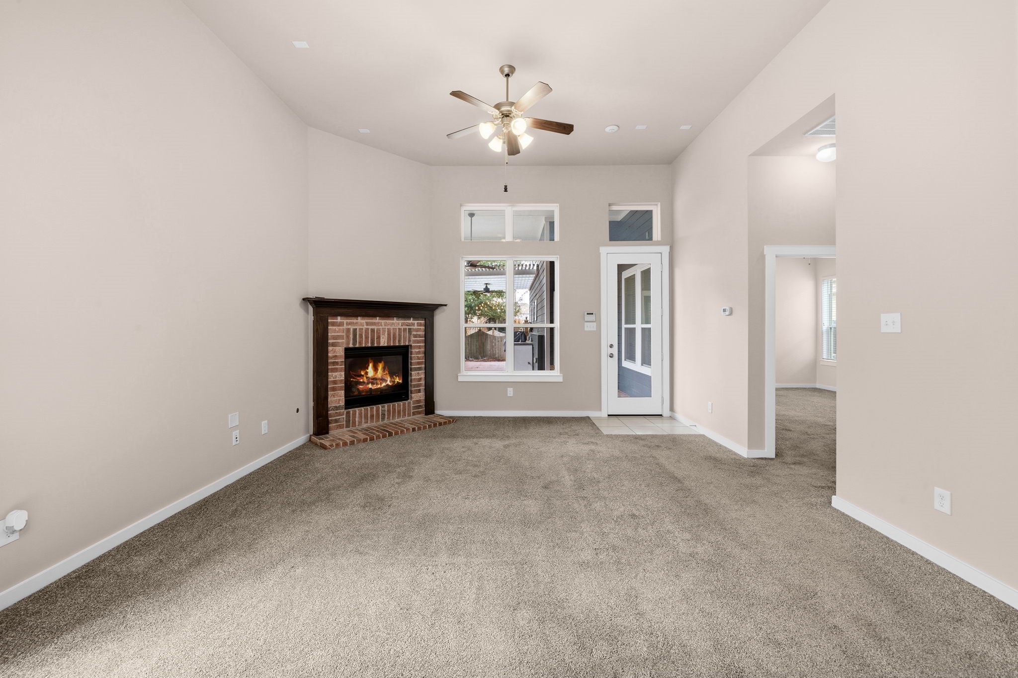 17019 Seminole Ridge Drive Cypress, TX 77433 - Photo 16 of 48 Spacious living room with soaring ceilings, plush carpet, and a cozy brick fireplace. Abundant natural light and an open layout create a warm, inviting space perfect for relaxing or entertaining.