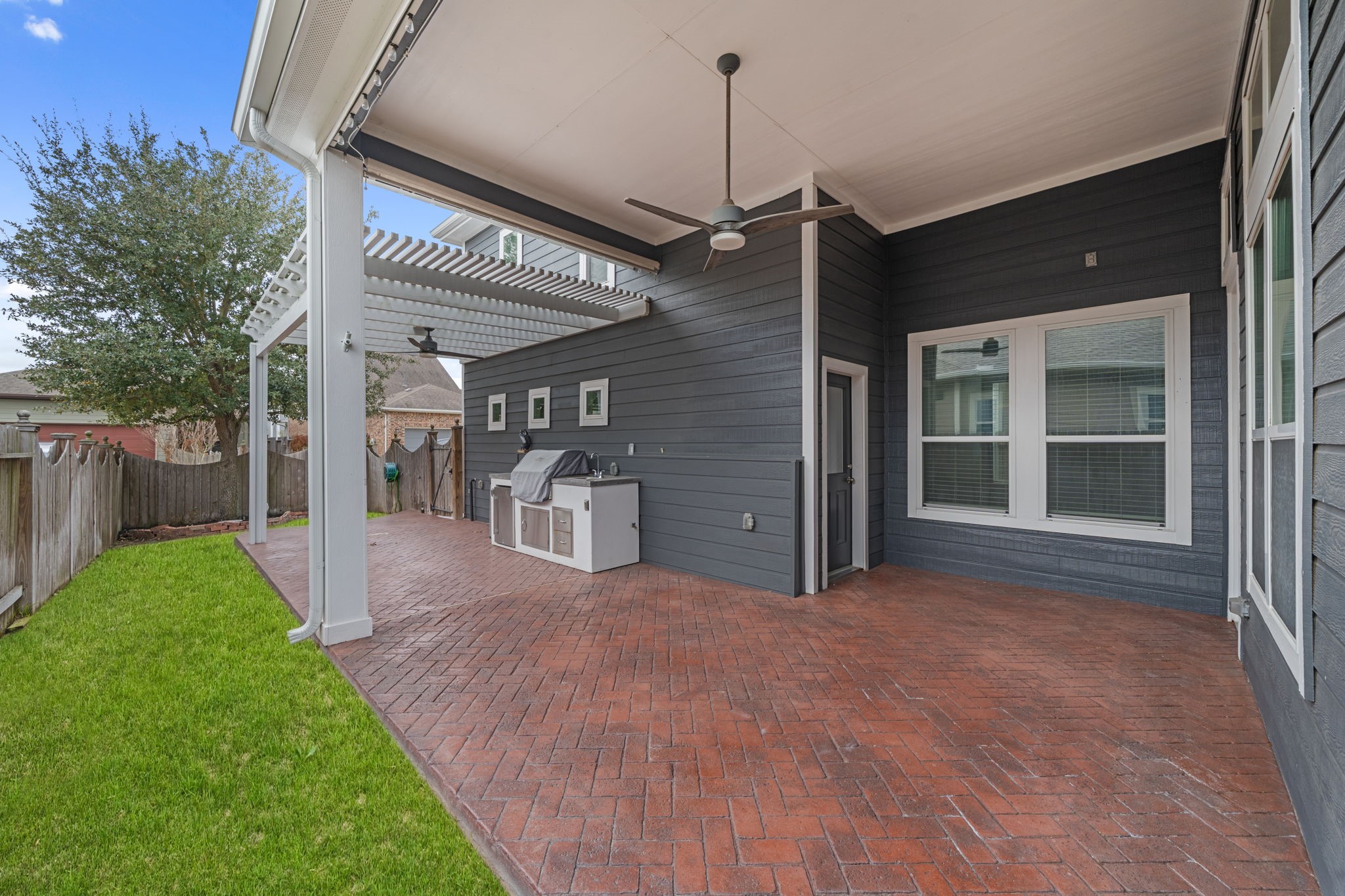 17019 Seminole Ridge Drive Cypress, TX 77433 - Photo 35 of 48 Inviting covered back patio with brick flooring, ceiling fan, and pergola extension—perfect for outdoor entertaining. Built-in grill area and private backyard create an ideal space for relaxing and gatherings year-round.