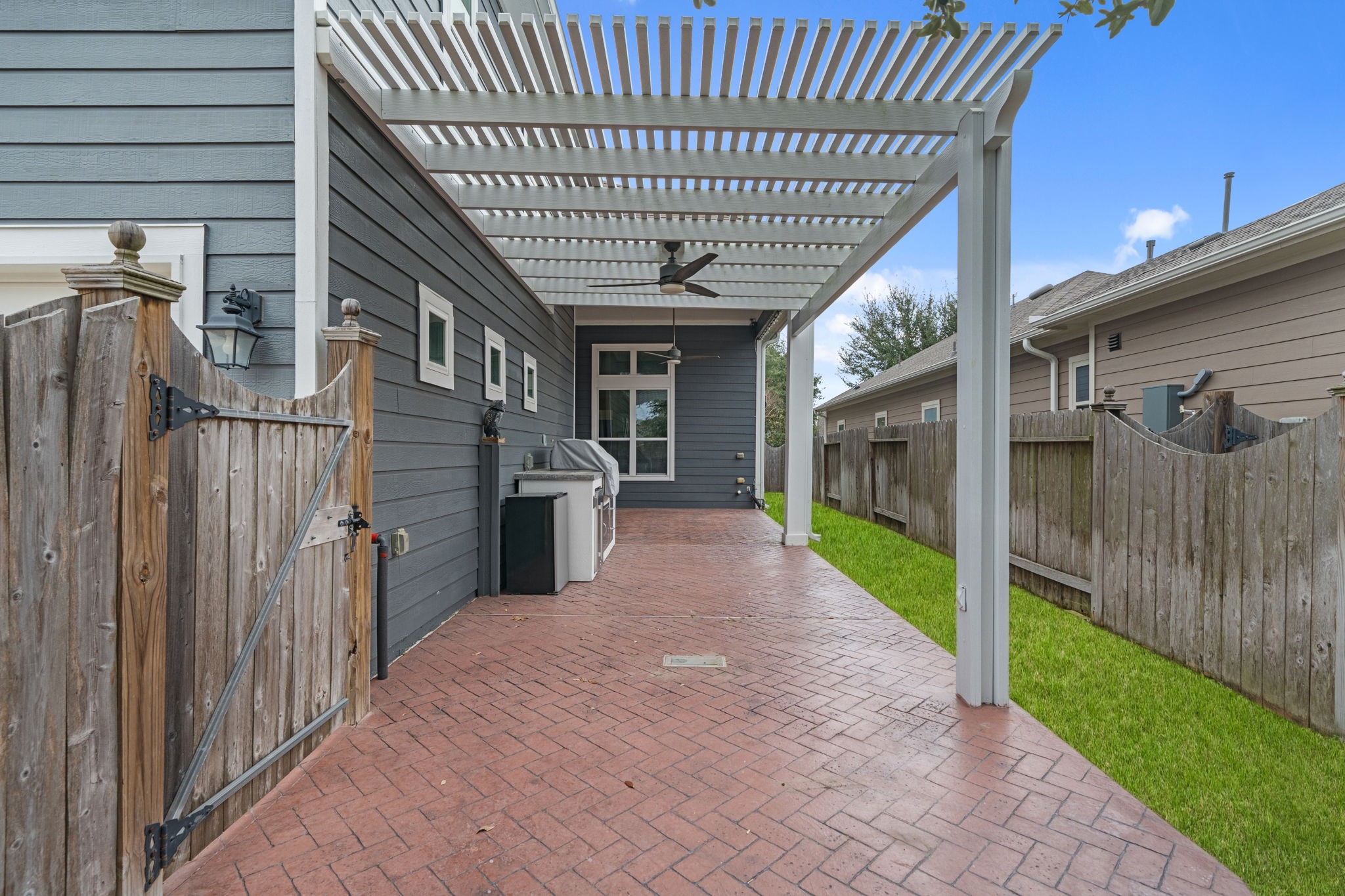 17019 Seminole Ridge Drive Cypress, TX 77433 - Photo 36 of 48 Extended covered patio with brick flooring and pergola detail, complete with ceiling fans for year-round comfort. Built-in grill area and fenced yard create the perfect setting for outdoor entertaining.