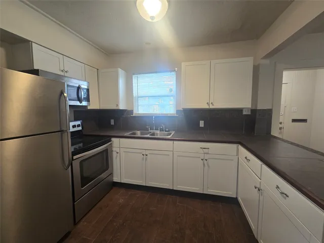 a kitchen with granite countertop stainless steel appliances a refrigerator a sink and cabinets