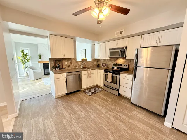 a kitchen with a refrigerator a stove top oven a sink dishwasher and white cabinets with wooden floor