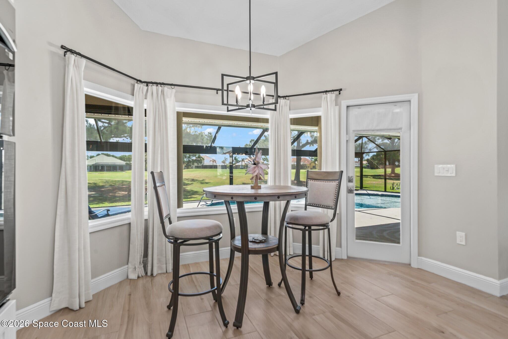 697 Spring Lake Drive Melbourne, FL 32940 - Photo 14 of 45 a dining room with wooden floor a chandelier a glass table and chairs