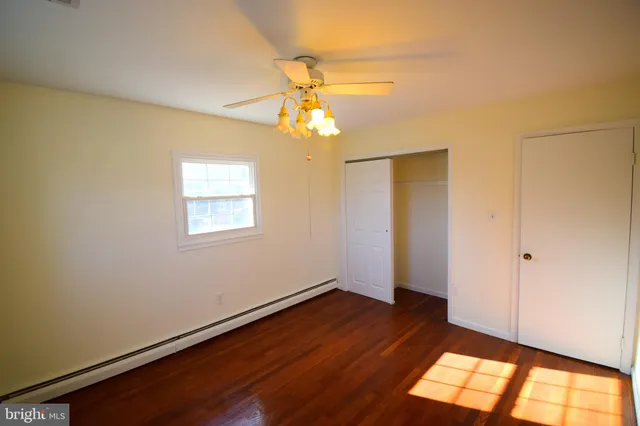 a view of empty room with wooden floor and fan