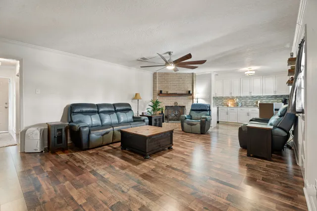 a living room with furniture kitchen view and a wooden floor