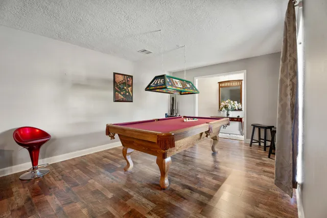 a room with pool table and wooden floor
