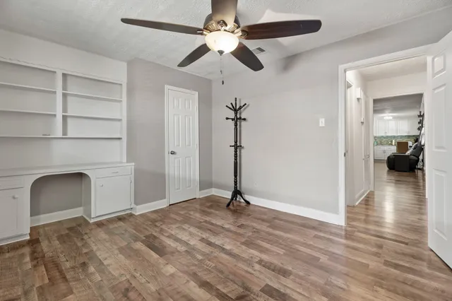 a view of a room with wooden floor and a ceiling fan