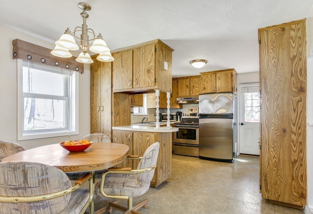 13 Cypress Road Natick, MA 01760 - Photo 4 of 24 a kitchen with stainless steel appliances granite countertop a dining table chairs and a refrigerator