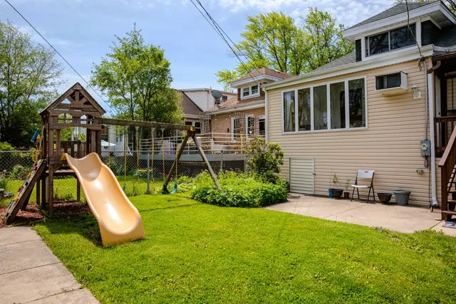 a view of a white house with a yard and lawn chairs under an umbrella